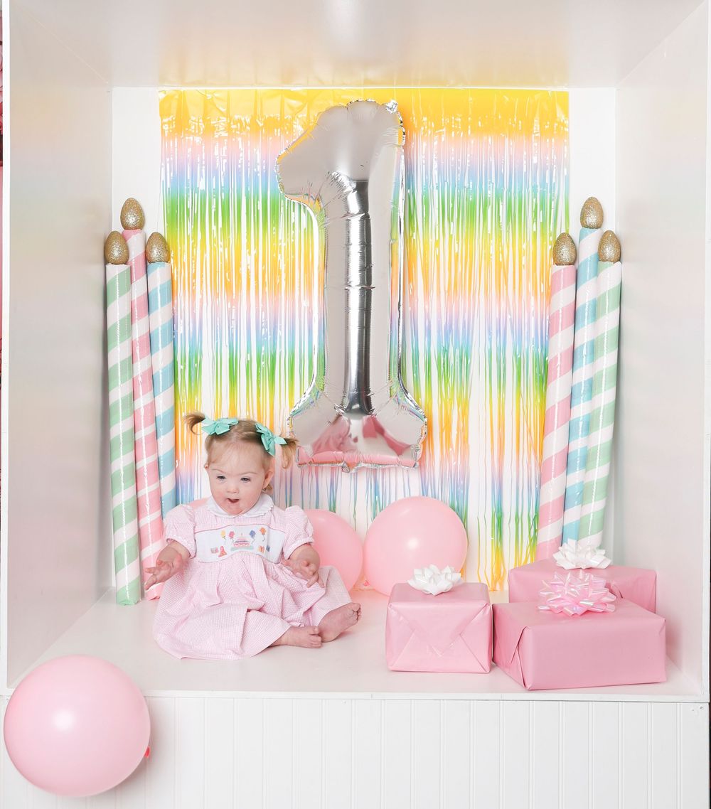 Pastel rainbow backdrop with pink decor and party supplies arranged for a whimsical celebration setup.