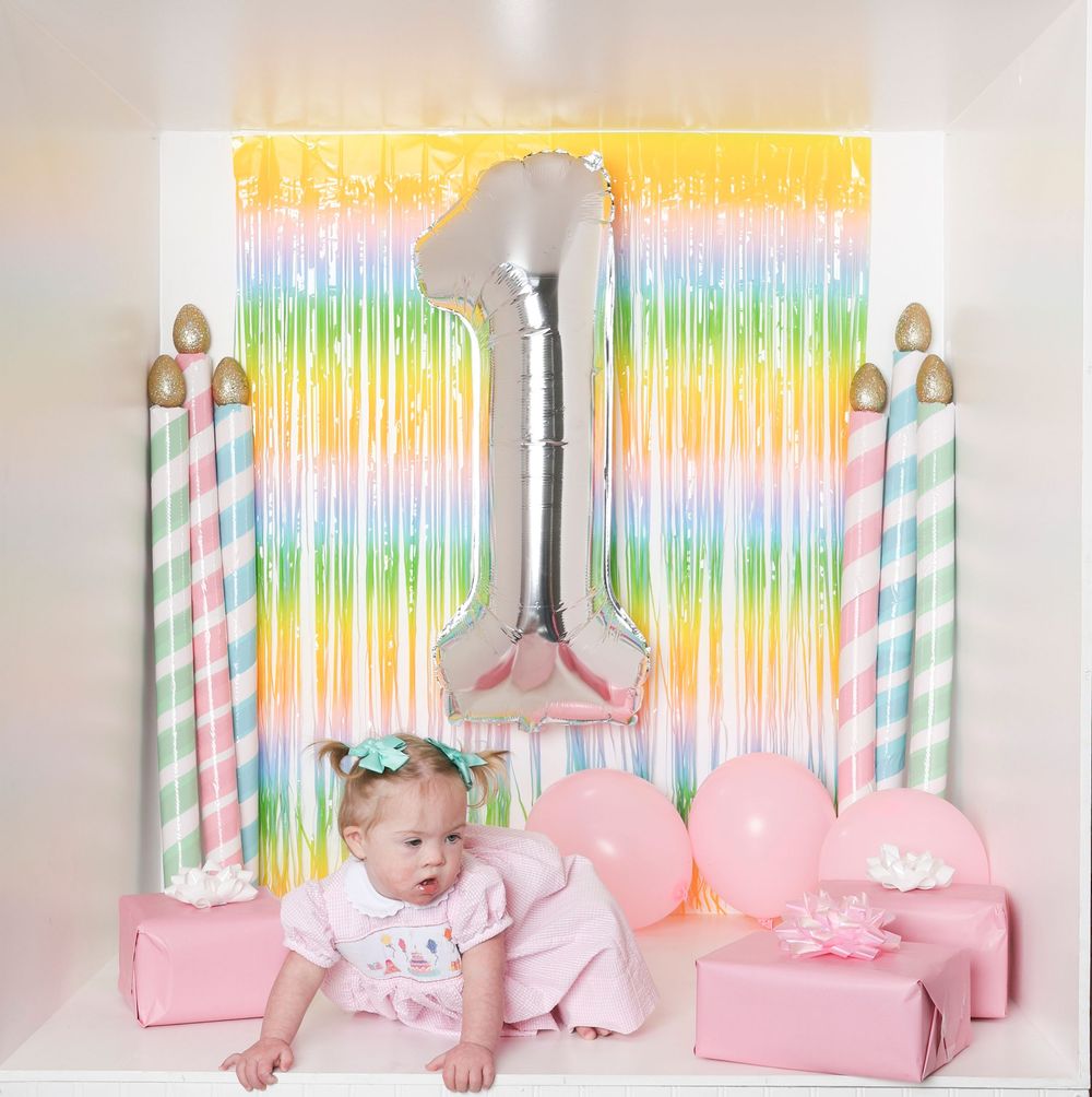 Rainbow and pink party setup with decorative streamers, candles, and pastel accents against a white backdrop.