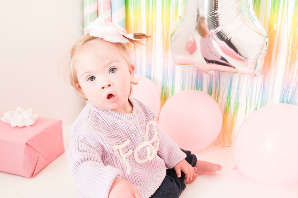 Pink and rainbow themed birthday party decorations with metallic streamers and pastel accents.