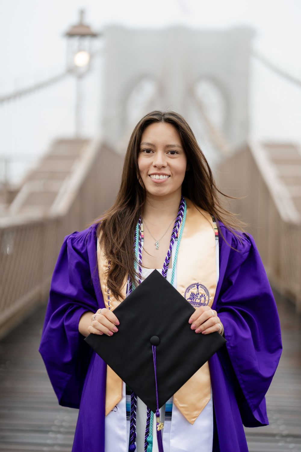A series of graduation photos showing someone in a purple graduation gown holding and displaying their mortarboard cap.