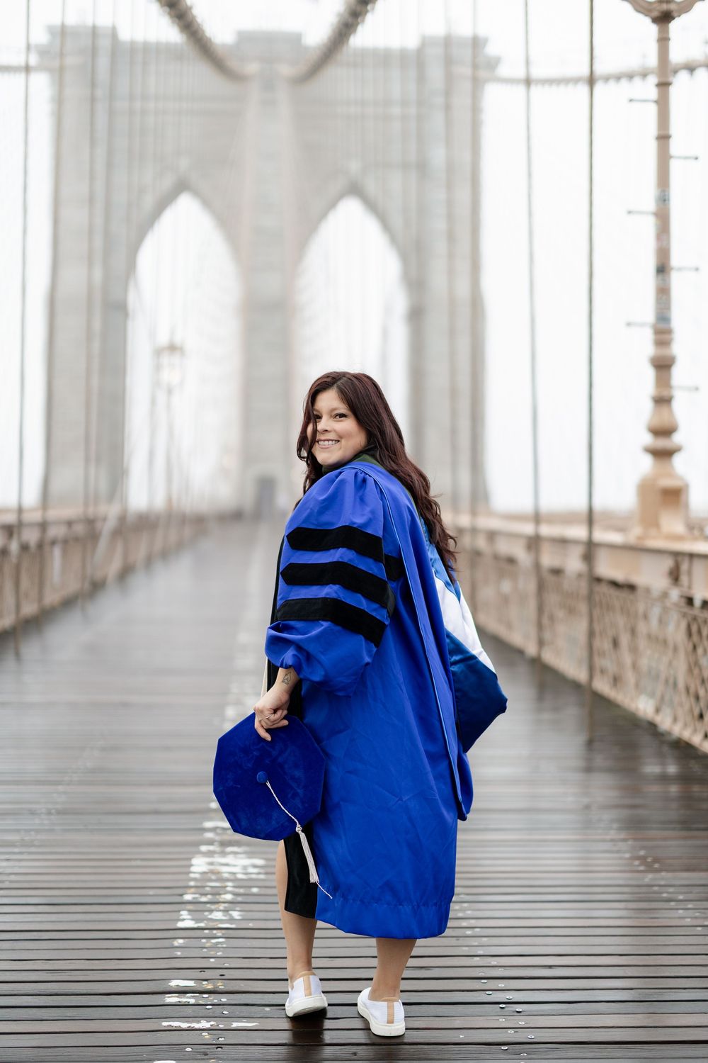 A series of photos showing a person in a blue graduation gown posing on the Brooklyn Bridge walkway.