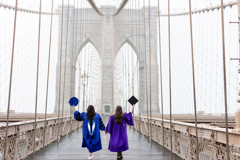 View of Brooklyn Bridge walkway with gothic arches and suspension cables stretching into the distance.