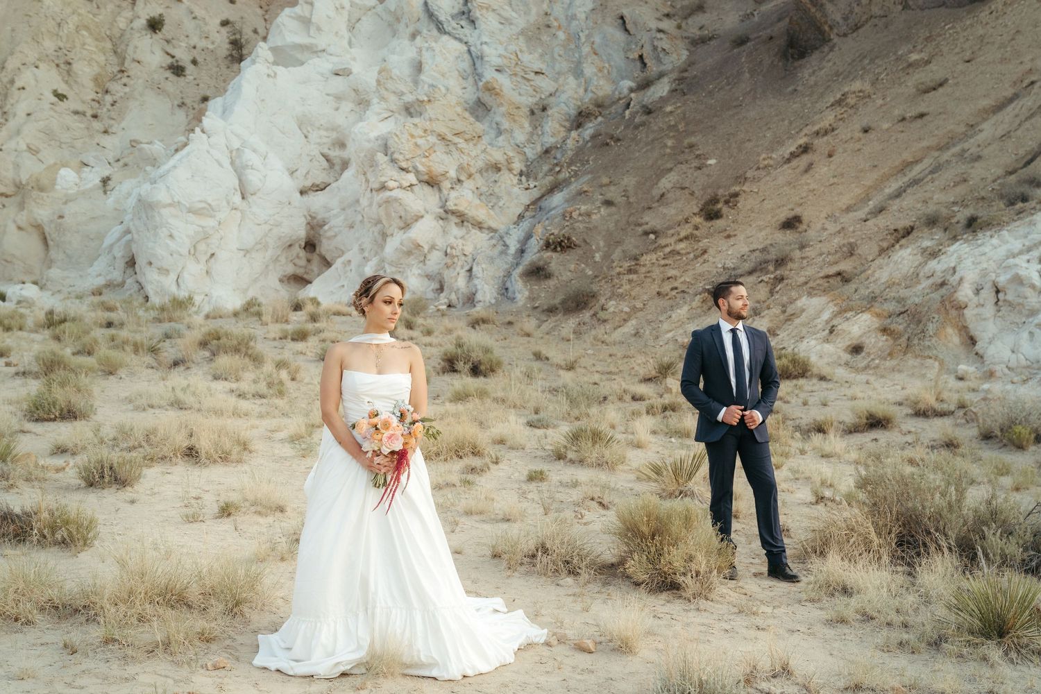 A man and a woman stand on a mountainside celebrating their wedding ceremony.