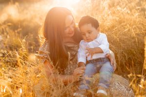 Tender moment between parent and child sitting in sun-drenched field.