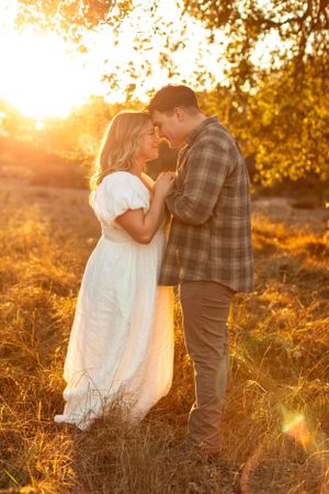 Intimate moment between couple touching foreheads in golden sunset light.