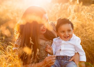 Parent and child sharing joyful moment in sunlit field during golden hour.