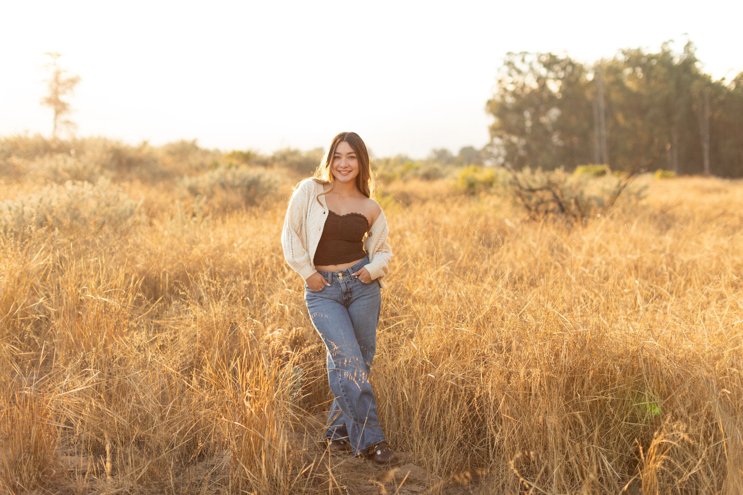 A sunset photoshoot in a golden field showcasing casual fall fashion and natural lighting effects.