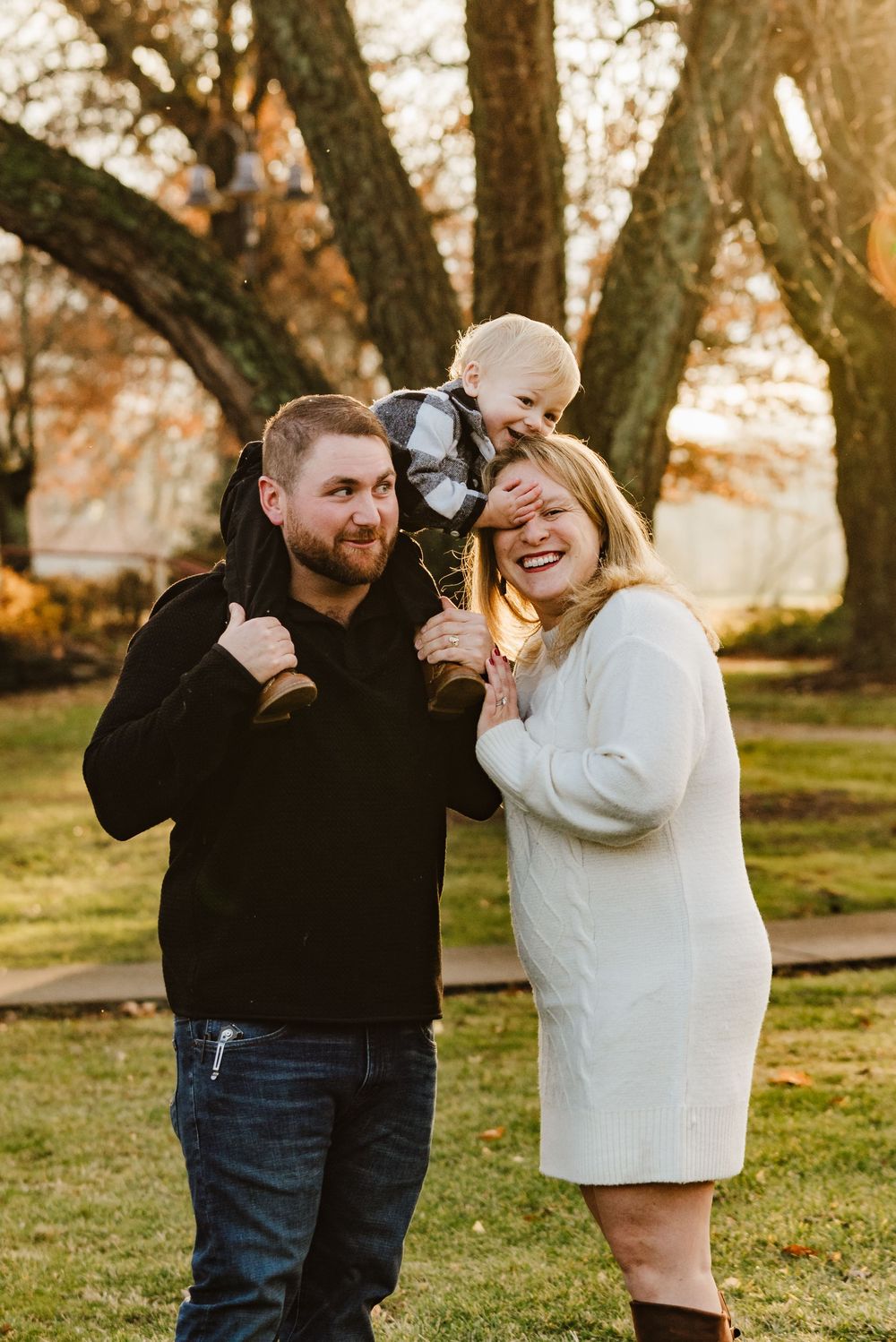 A couple shares joyful laughter together during a golden hour photoshoot in a park setting.