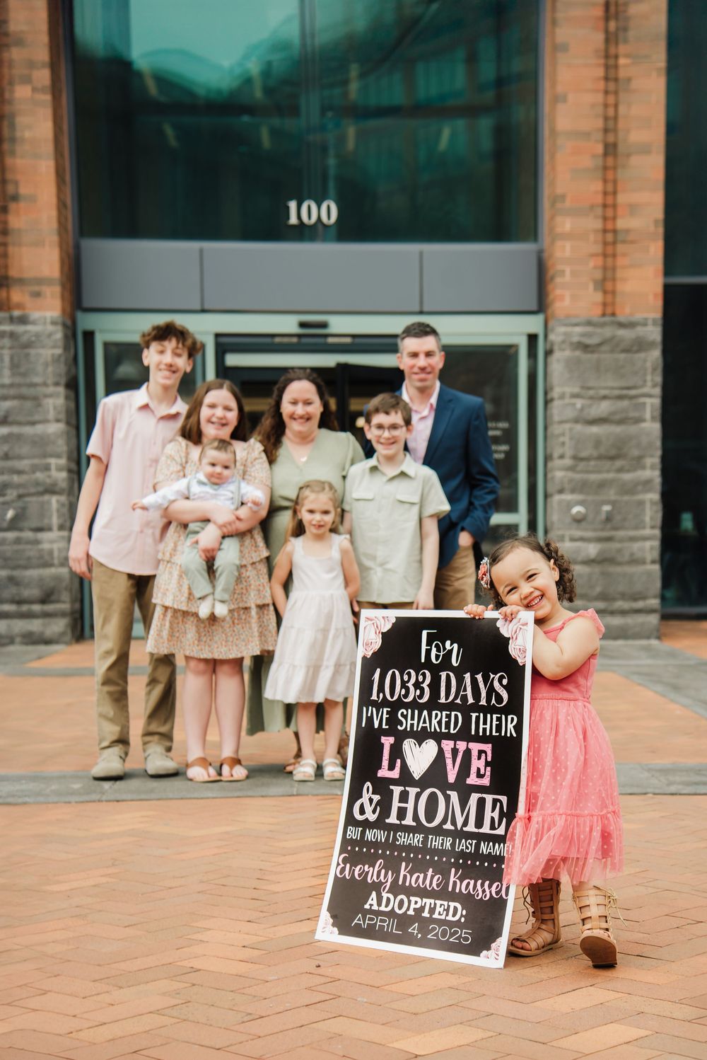 A series of adoption milestone photos showing a family posing with chalkboard signs on a brick patio.
