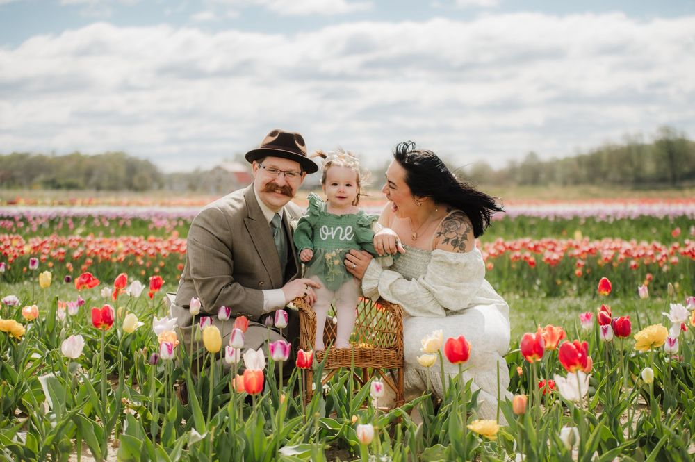 A couple shares an intimate moment in a vibrant tulip field on a cloudy spring day.