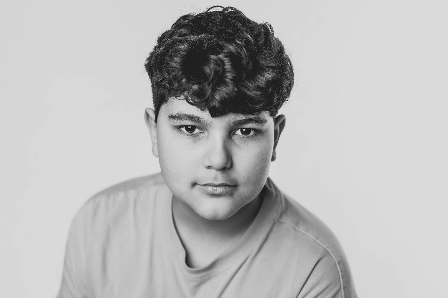 A black and white portrait photograph of someone wearing a light colored shirt against a plain background.