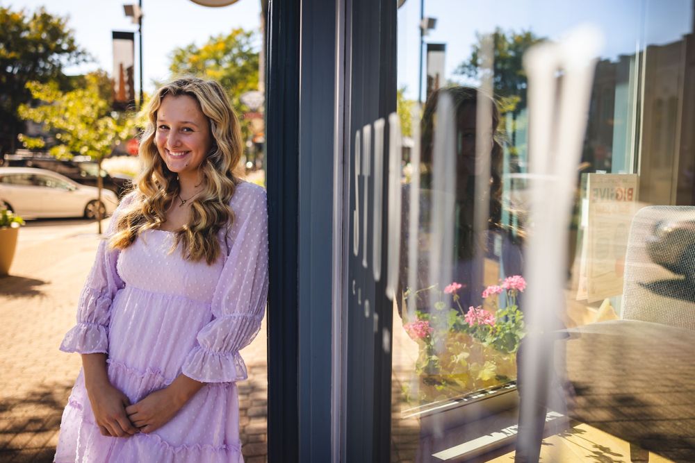 Outdoor portrait in lavender dress with sunlit buildings in background.