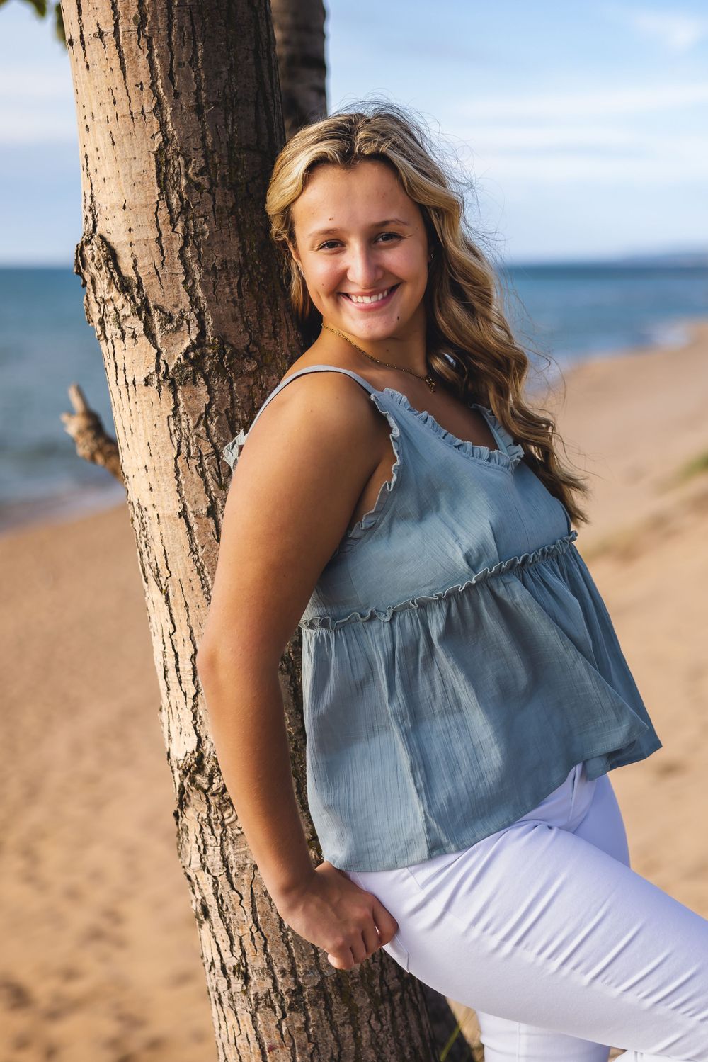 Casual summer beach portrait with denim top and white pants against palm tree.