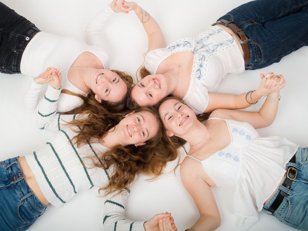 Four sisters lie in a circle, smiling, captured in a family photo by Abigail's studio in High Wycombe.