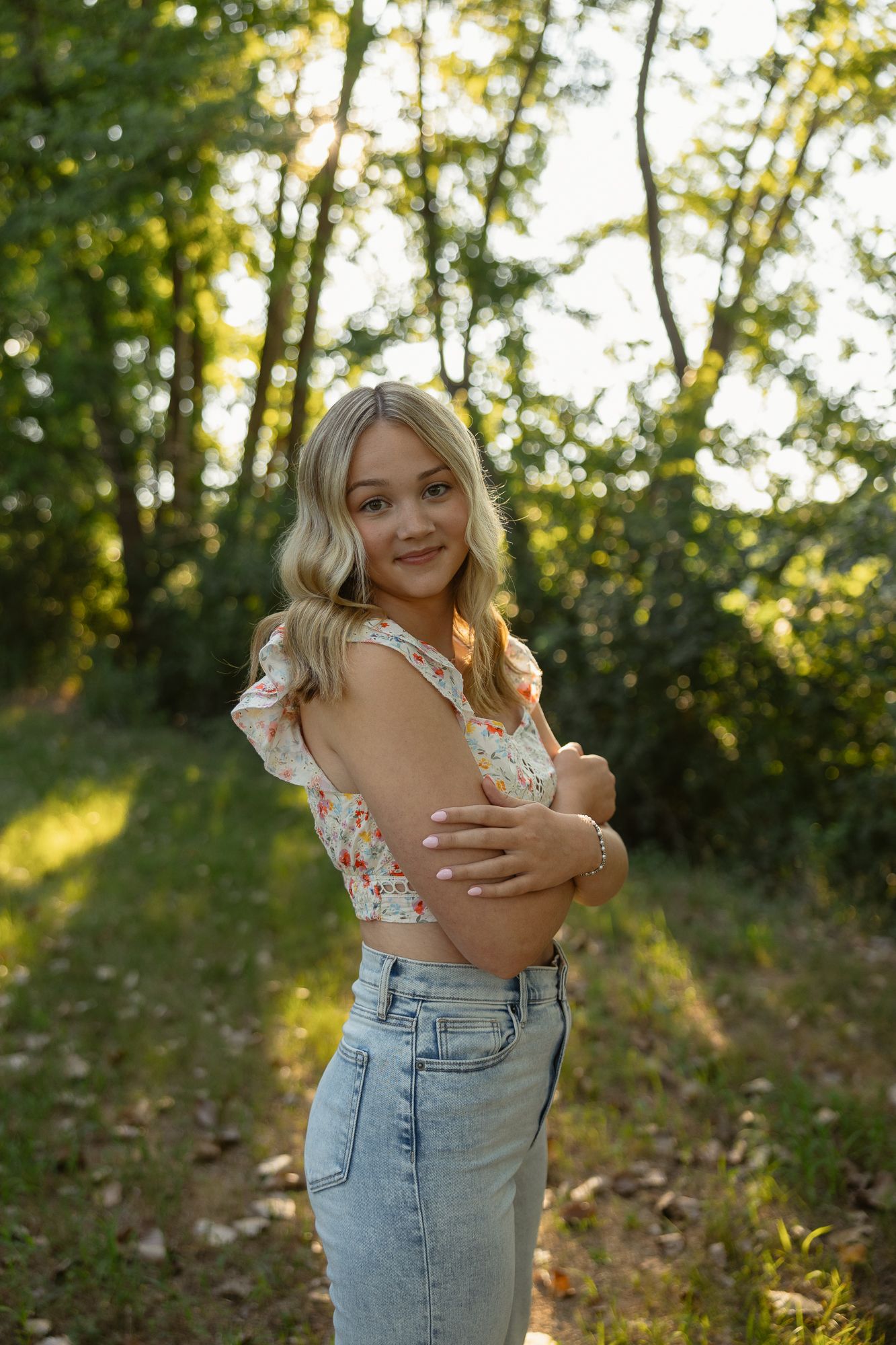 Outdoor portrait series in golden sunlight showing casual summer style with light wash denim and floral details.