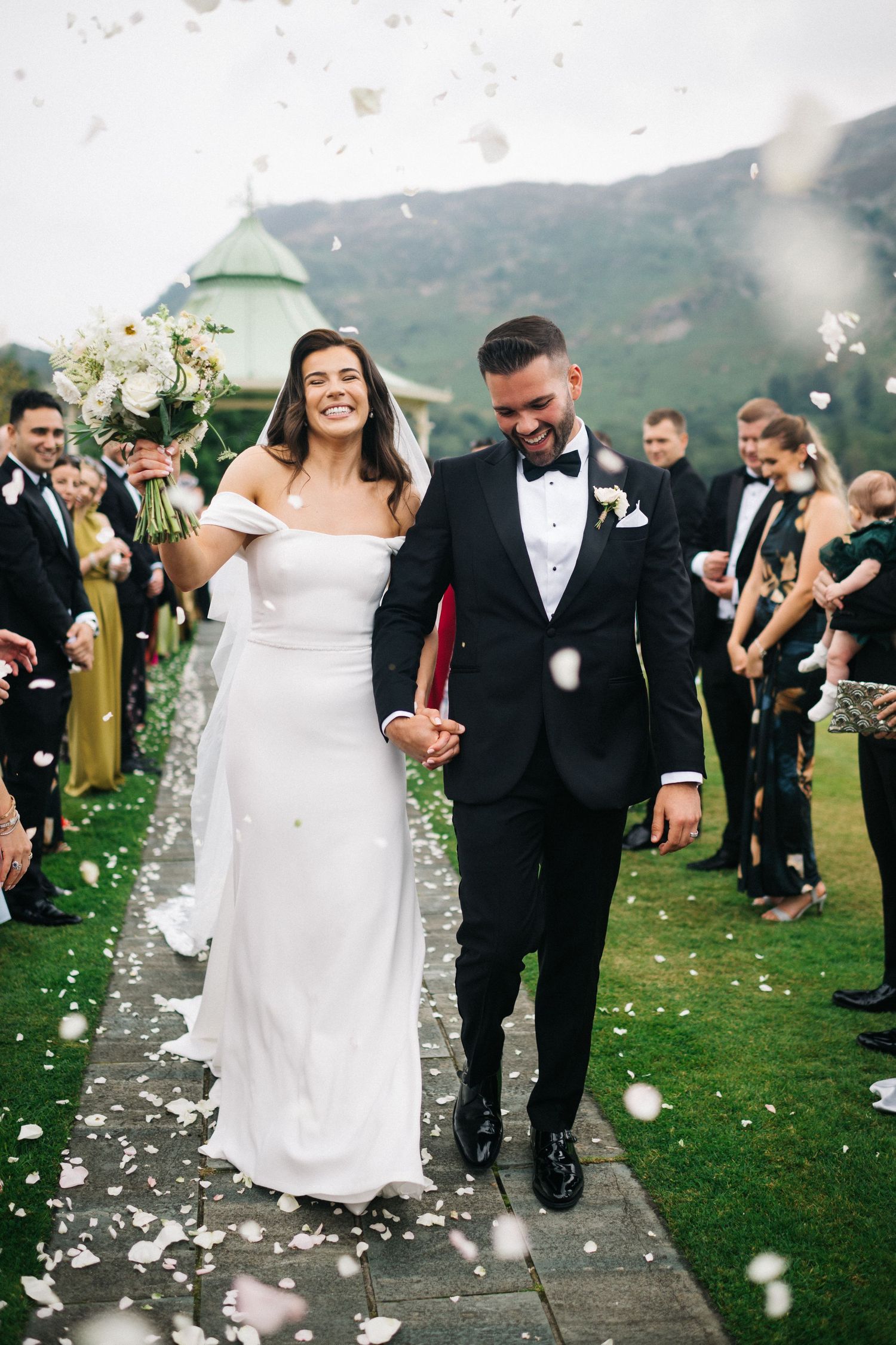A romantic wedding couple dances together on a lakeside dock with mountains and moody skies in the background at the Inn on the Lake.