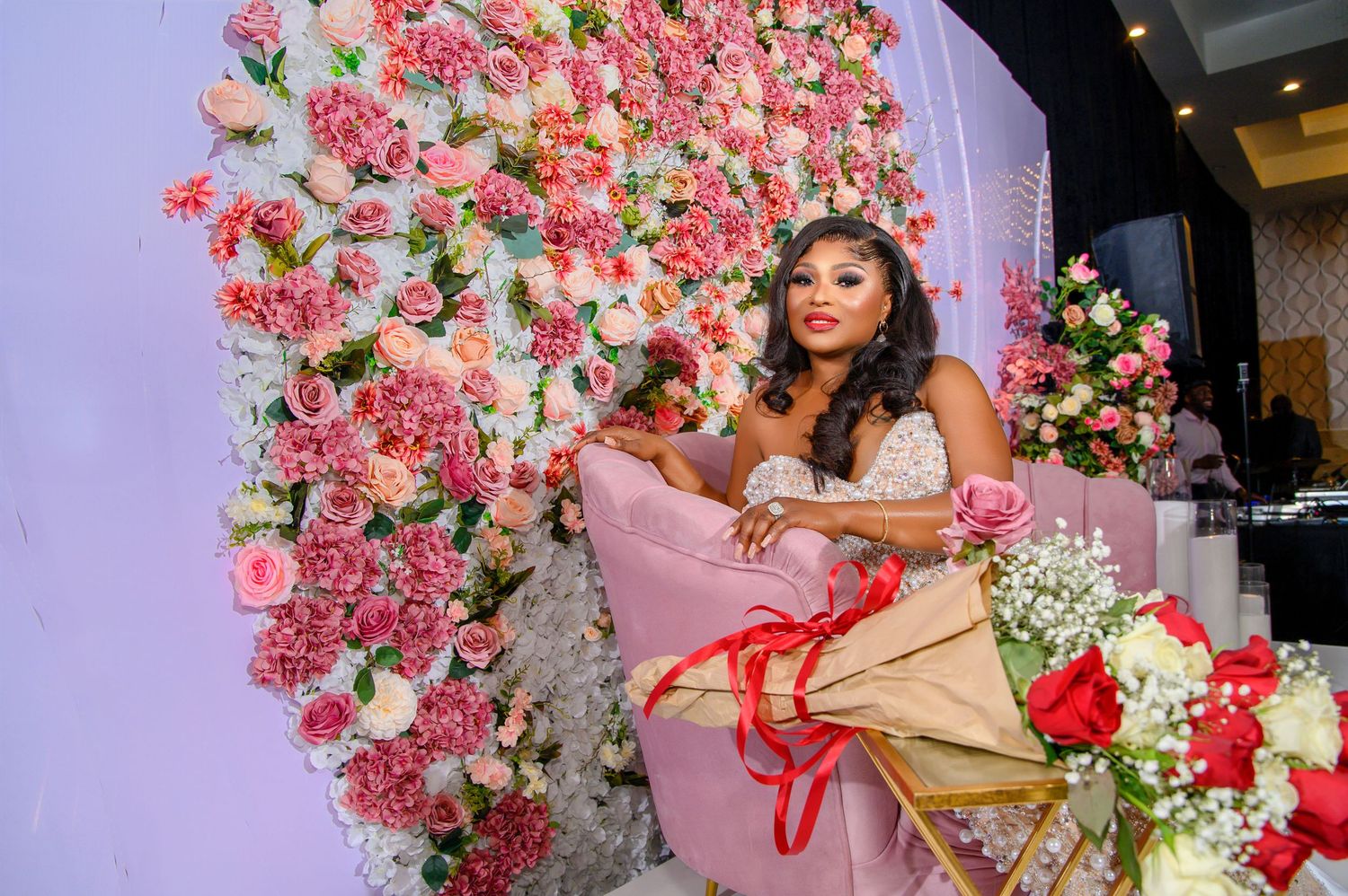Pink floral wall backdrop with cascading roses creates a romantic atmosphere.