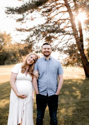 Couple posing together at sunset in park with golden sunlight filtering through trees.