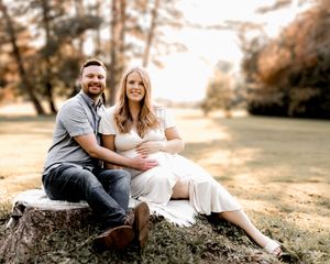 Couple relaxing on grass during golden hour photoshoot in park setting.
