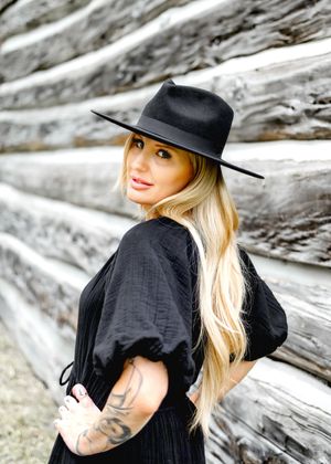 Stylish portraits featuring black hat and outfit against textured wooden backdrop.