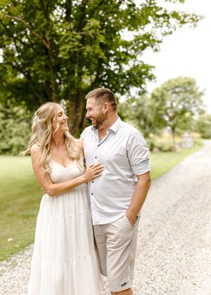 A romantic moment shared on a gravel path surrounded by lush green scenery.