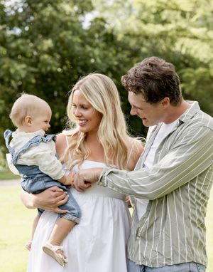 A tender family moment shared on a sunny afternoon in a green park setting.