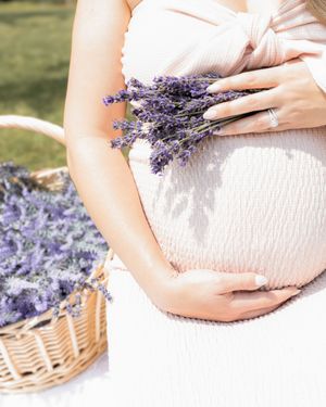 Delicate lavender sprigs rest against a soft white maternity dress in a series of gentle poses.