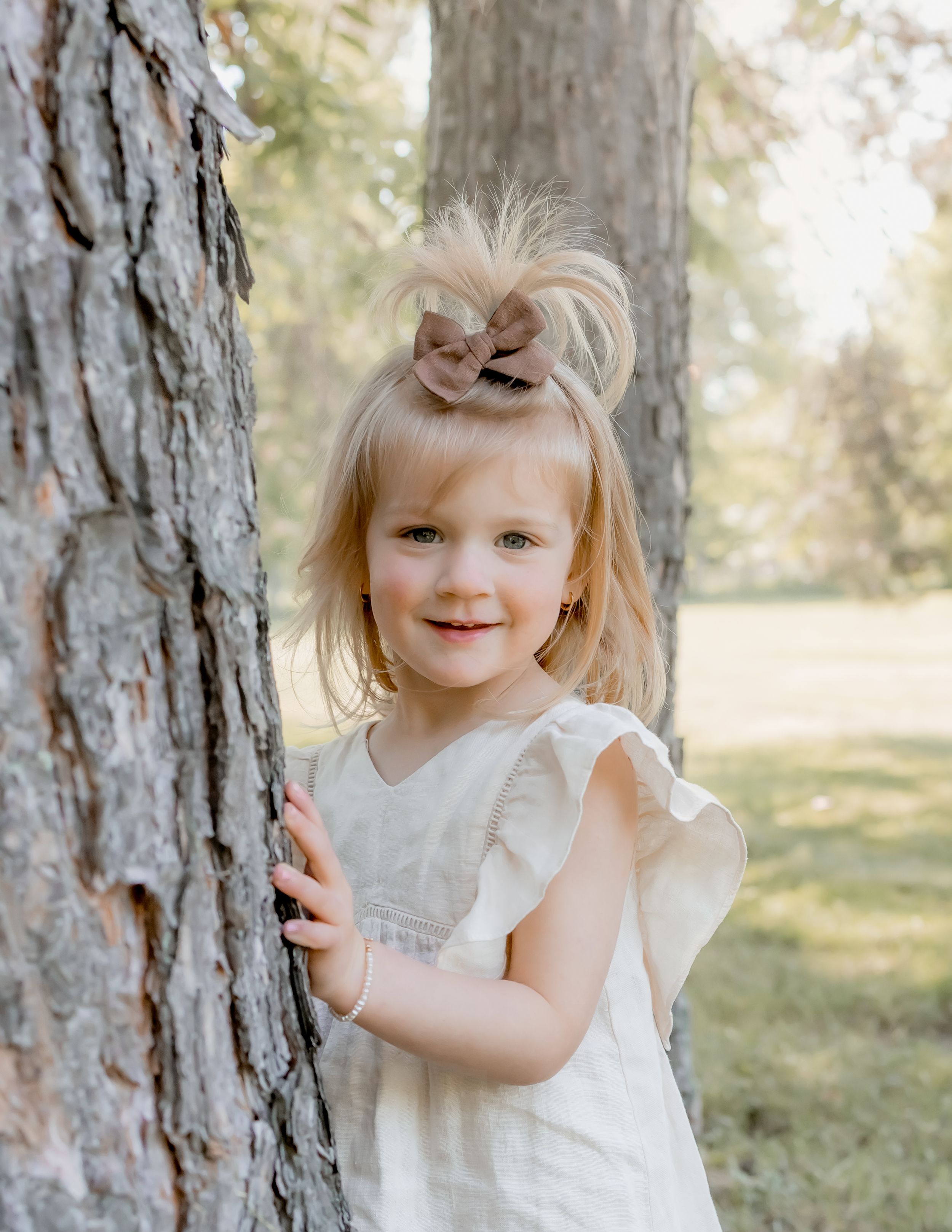Little girl popping out from behind tree during a spring mini photography session