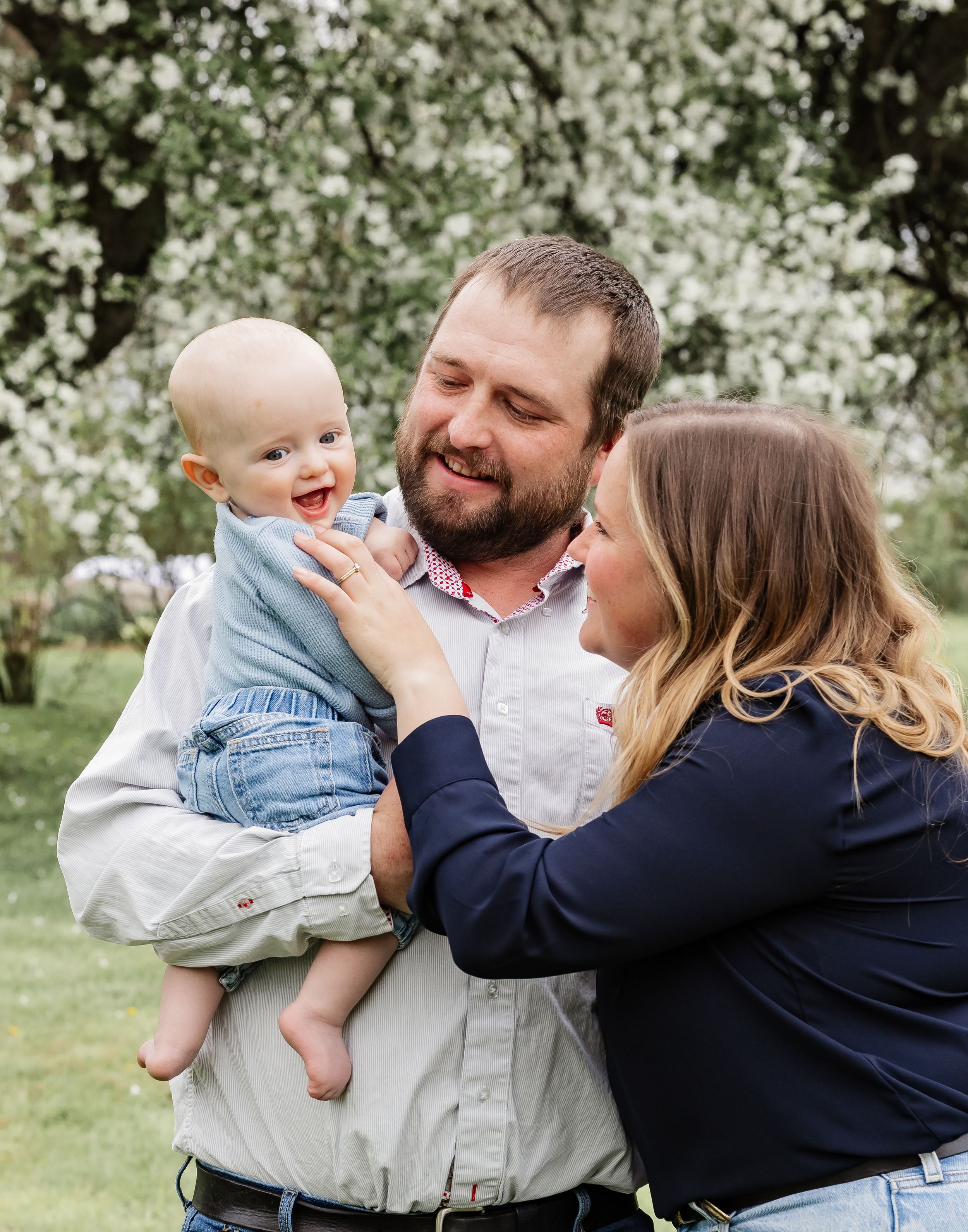 A joyful outdoor family moment captured among blooming spring trees.