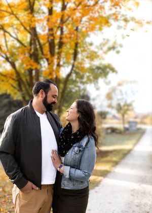 A couple shares tender moments together under golden autumn trees in a park setting.