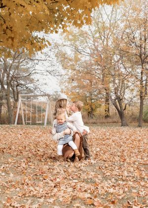 A heartwarming autumn scene with fallen leaves and playground equipment in the background.