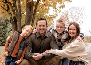 An autumn family portrait with fall foliage creating a warm golden backdrop.