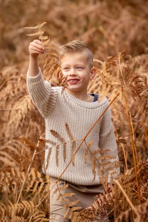 foto in bruintinten. Kinderportret buiten in Ommen. Jongetje gekleed in bruintinten tussen de varens.
