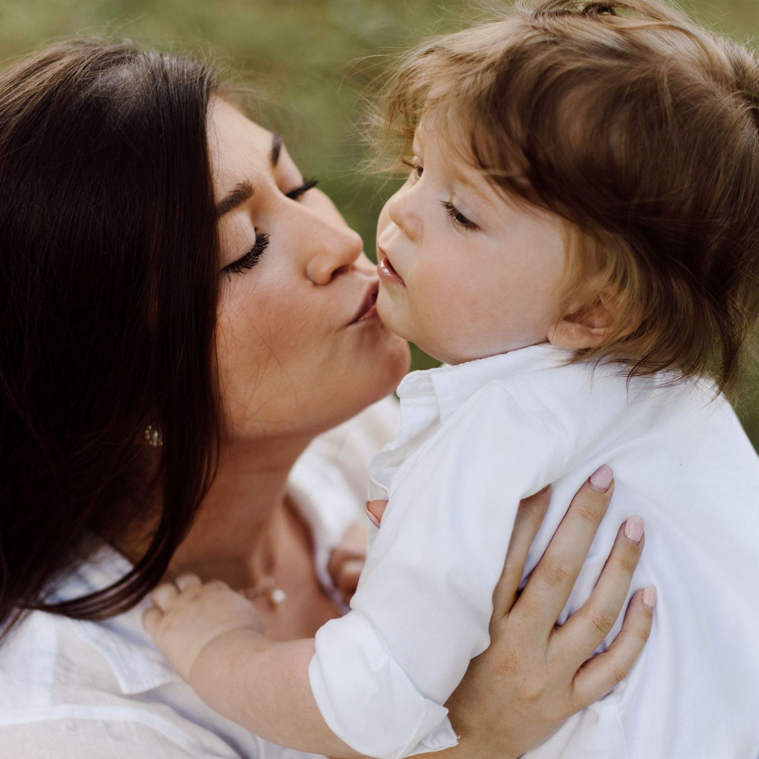 Series of loving kisses and embraces between parent and child in white clothing.