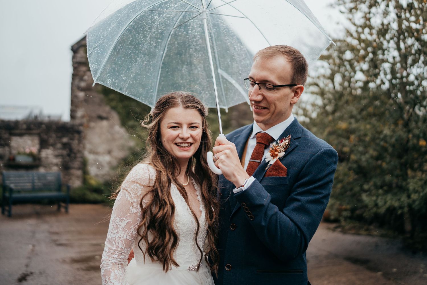 Candid wedding moments captured under umbrellas on a rainy day with joyful expressions.