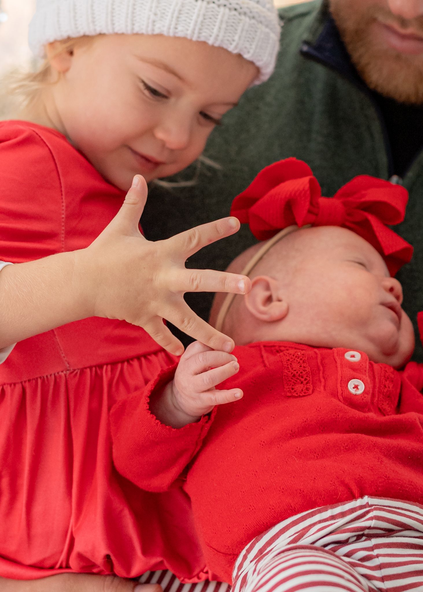 Tender moment captured indoors with soft lighting and festive holiday decorations.