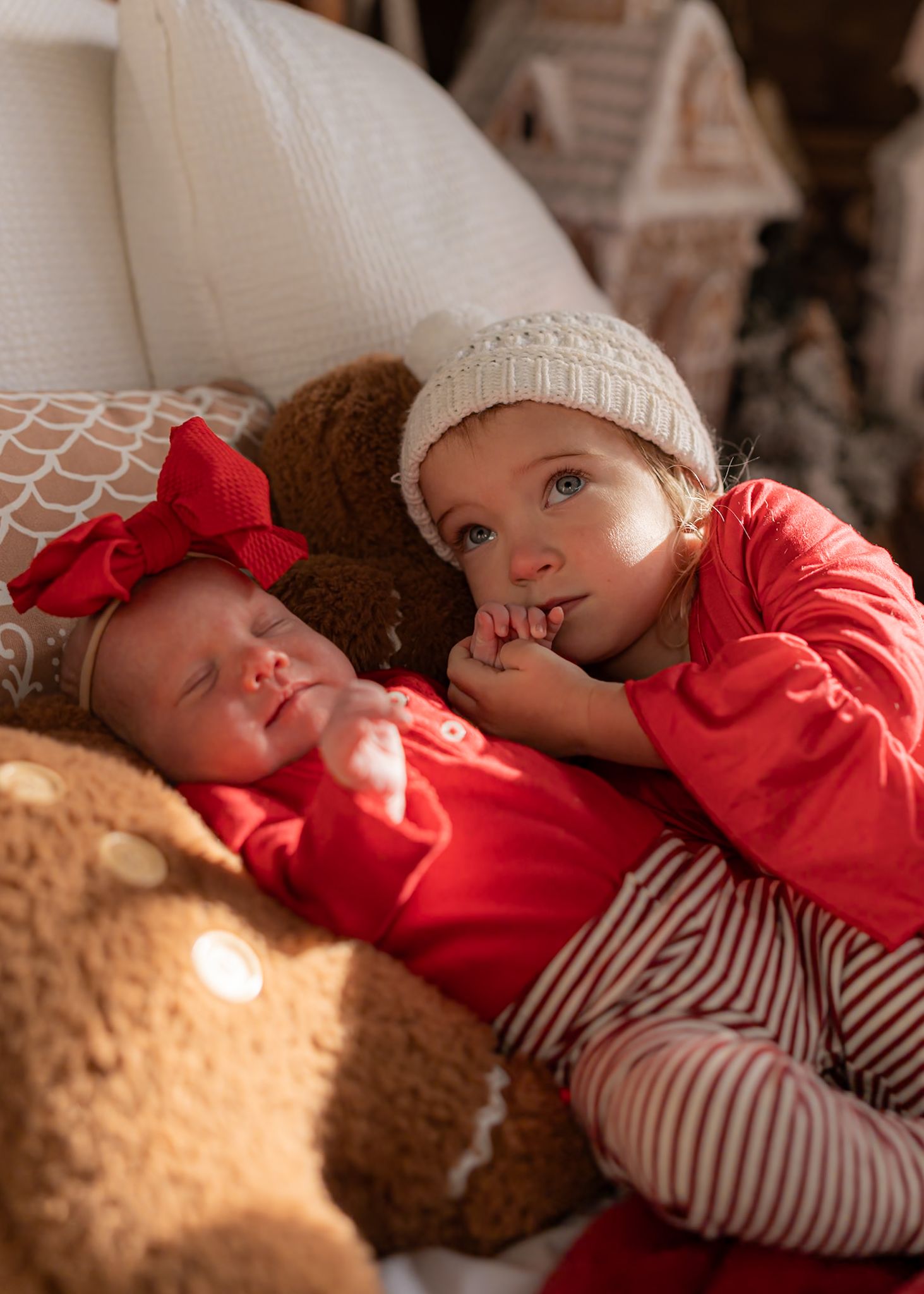 Holiday portrait showing red clothing and white knit hat against soft beige background.