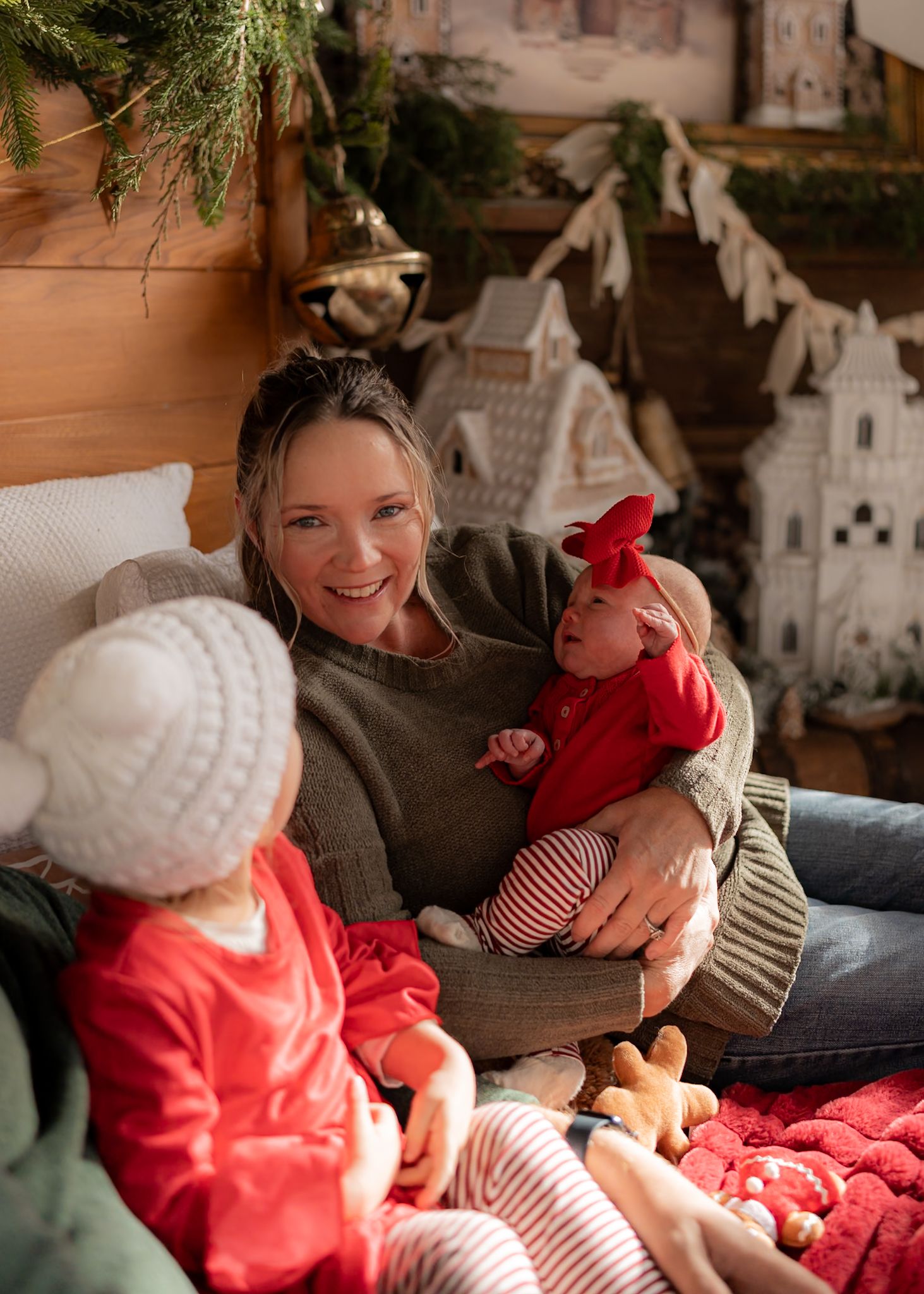 Warm holiday scene with Christmas village decorations and cozy seating area.