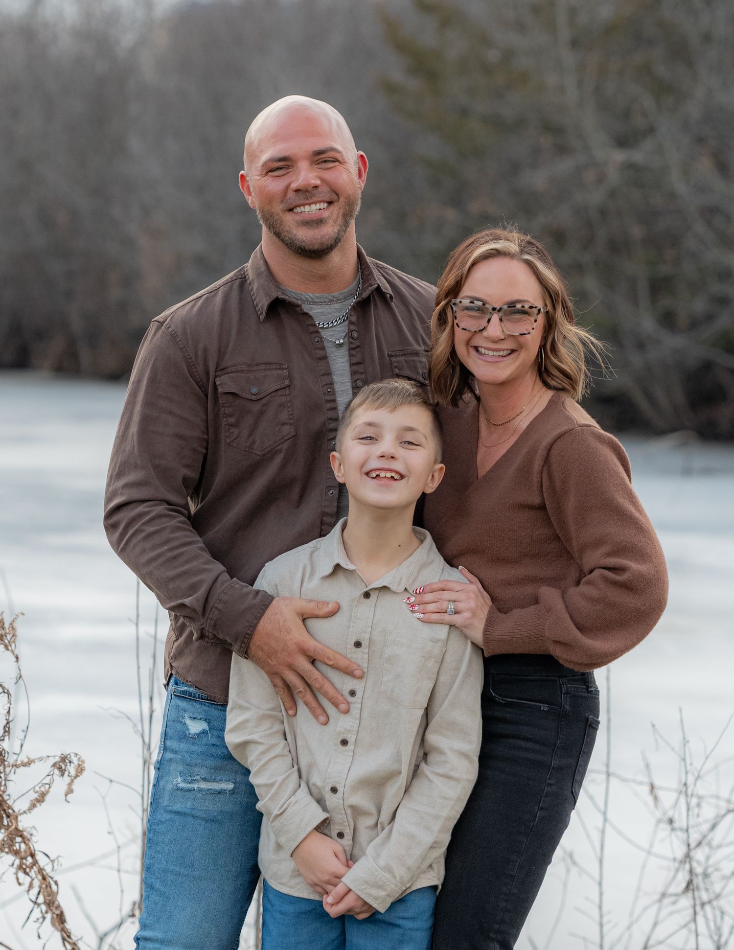 Family portrait in casual winter attire against snowy landscape.