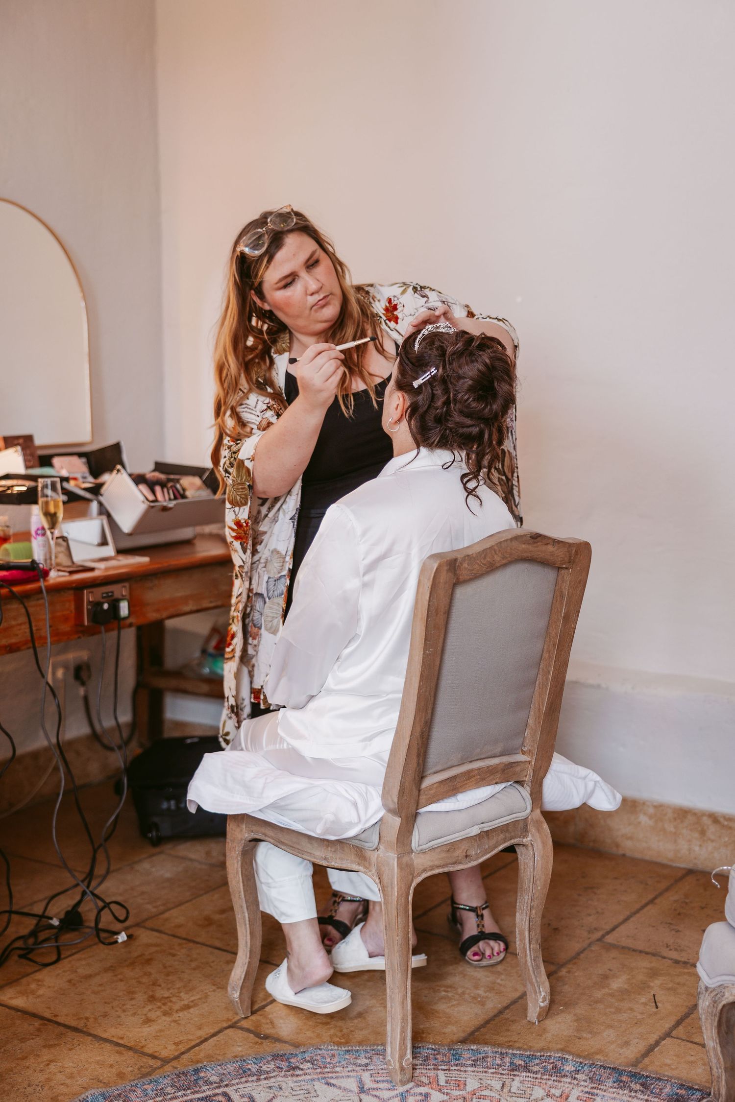 Getting ready scene with antique wooden chairs and white robes in a rustic indoor setting.