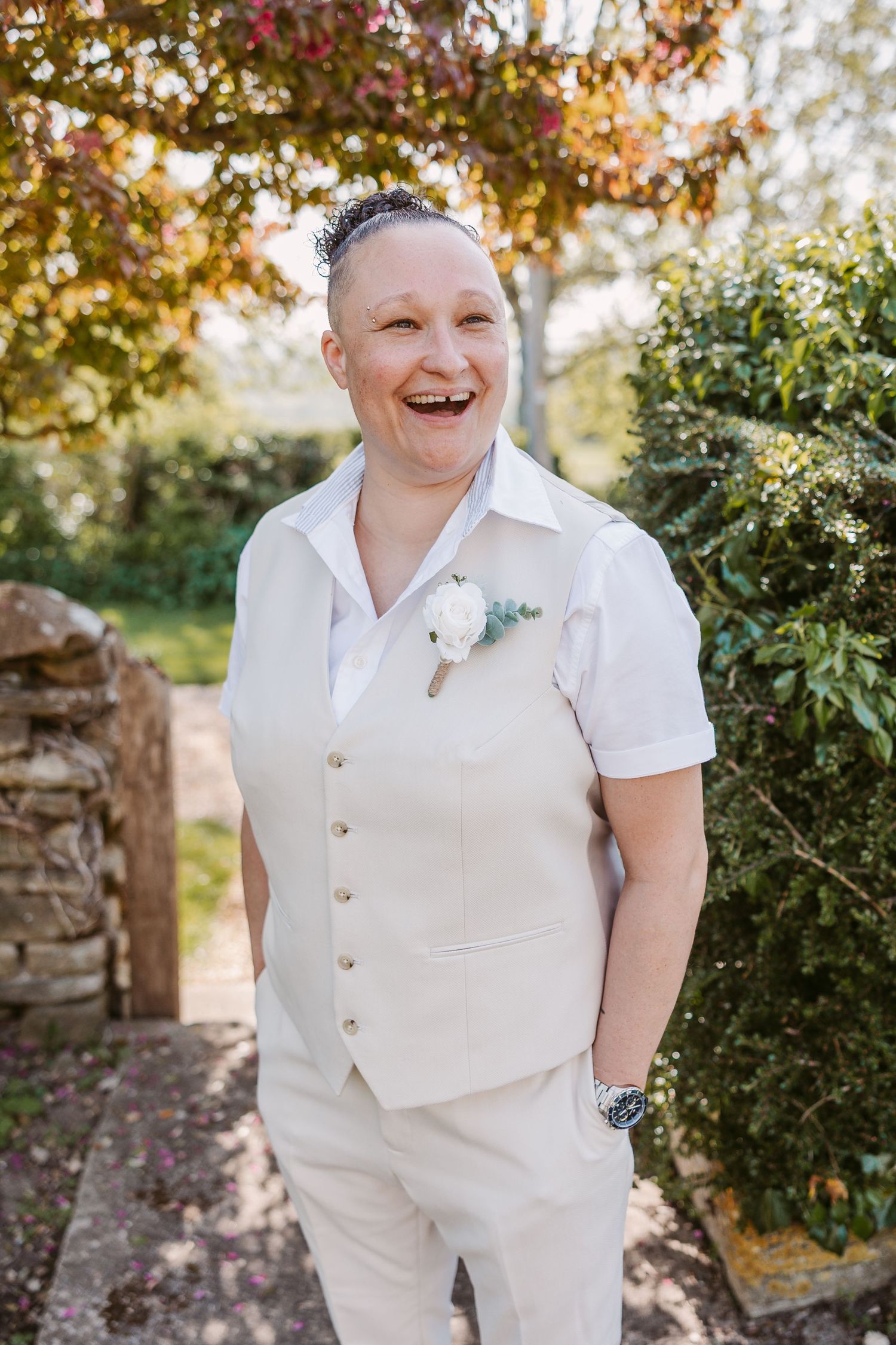 Wedding portraits in a garden setting with sunlit foliage and stone walls.
