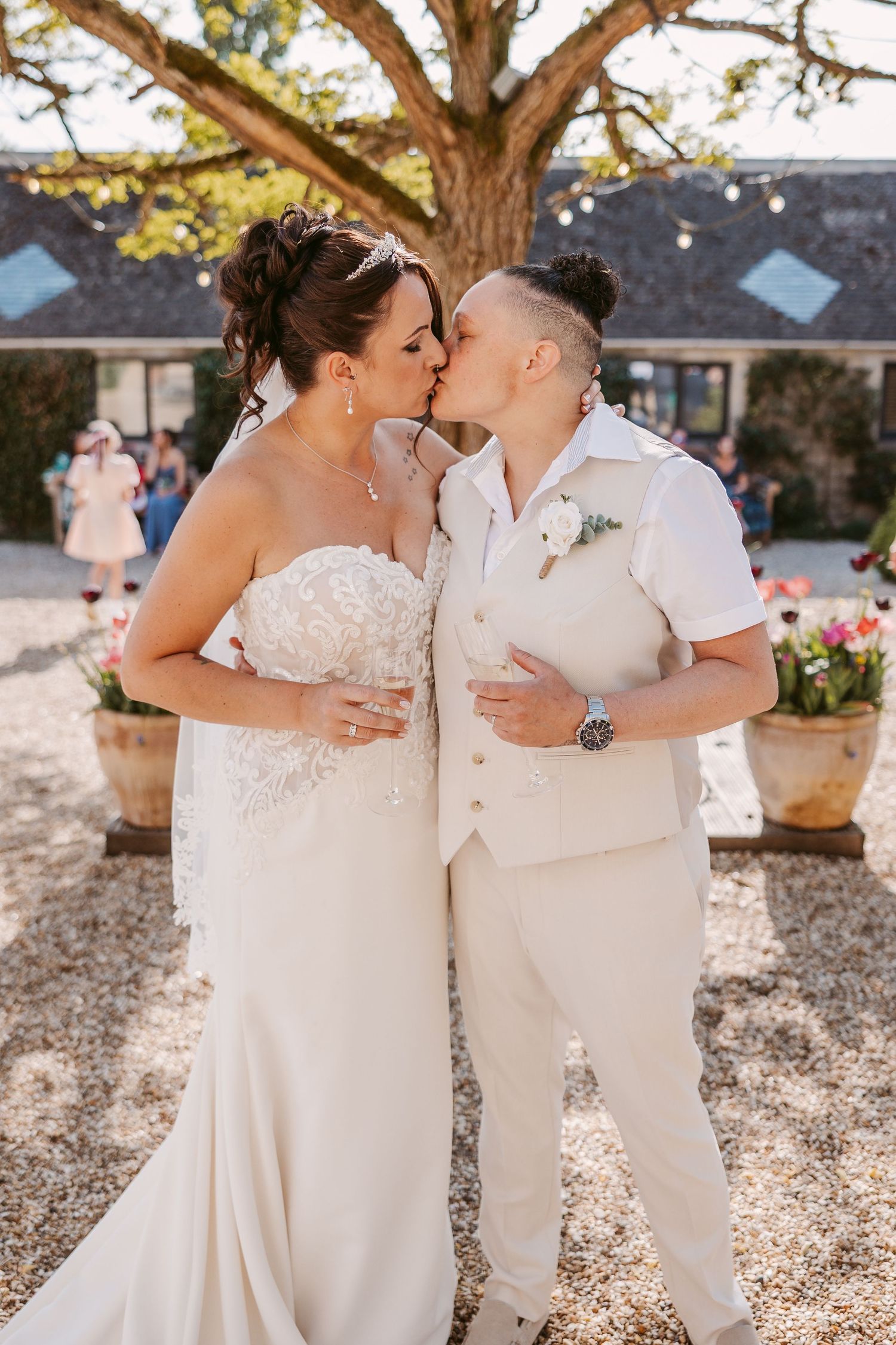 A couple shares their first kiss as newlyweds in an outdoor garden setting.
