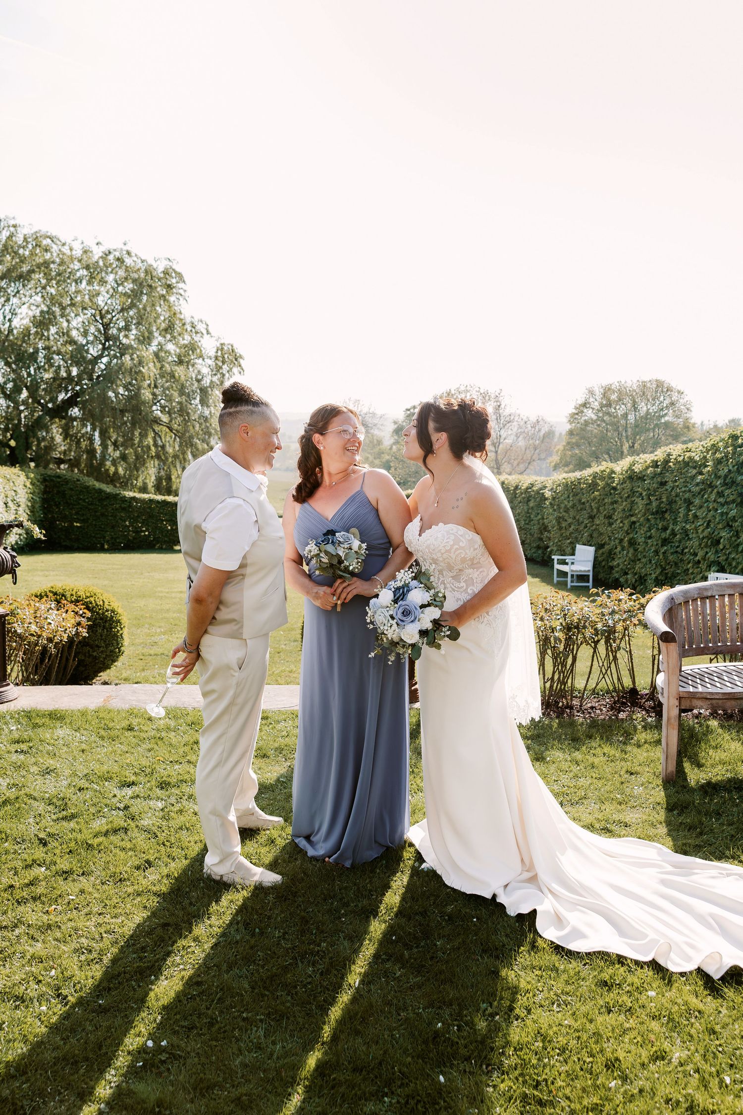 Wedding party poses for photos on grassy lawn during golden hour.