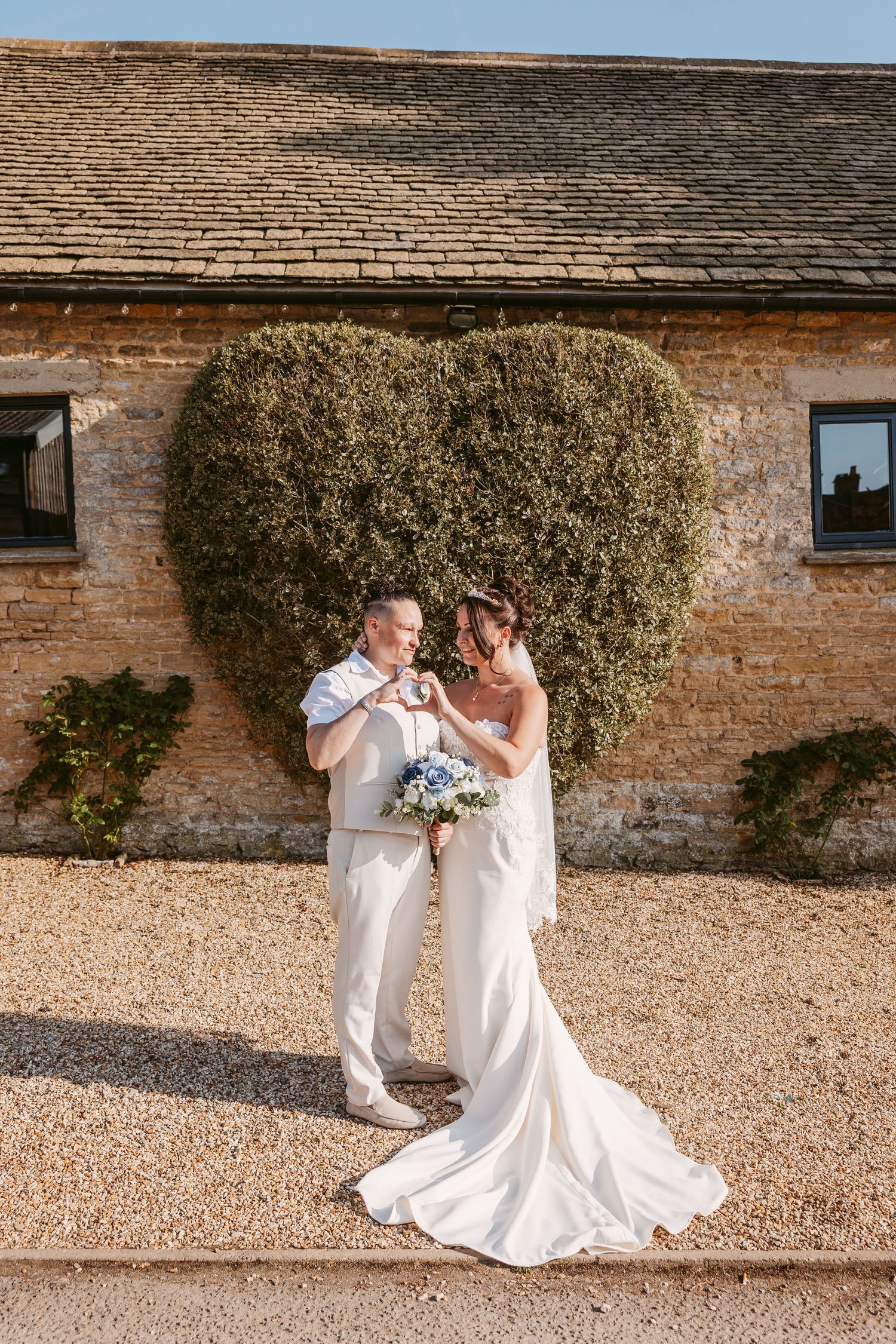 Romantic wedding portraits against rustic brick wall and gravel path backdrop.