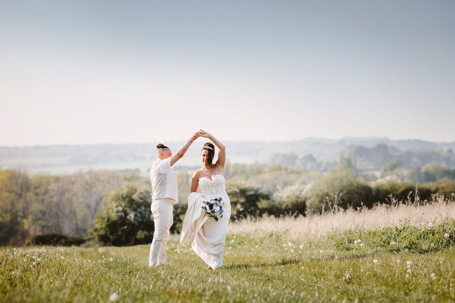 Wedding couple walking through a sun-drenched meadow on their special day.