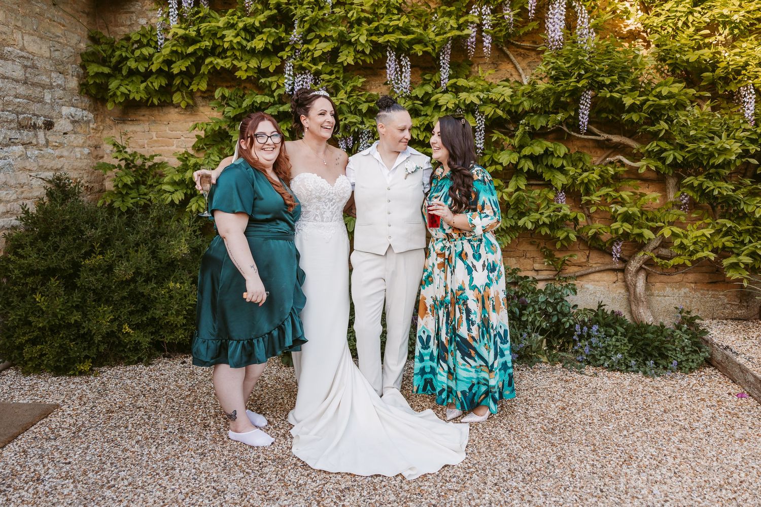 Wedding party gathering for casual photos against an ivy-covered brick wall.