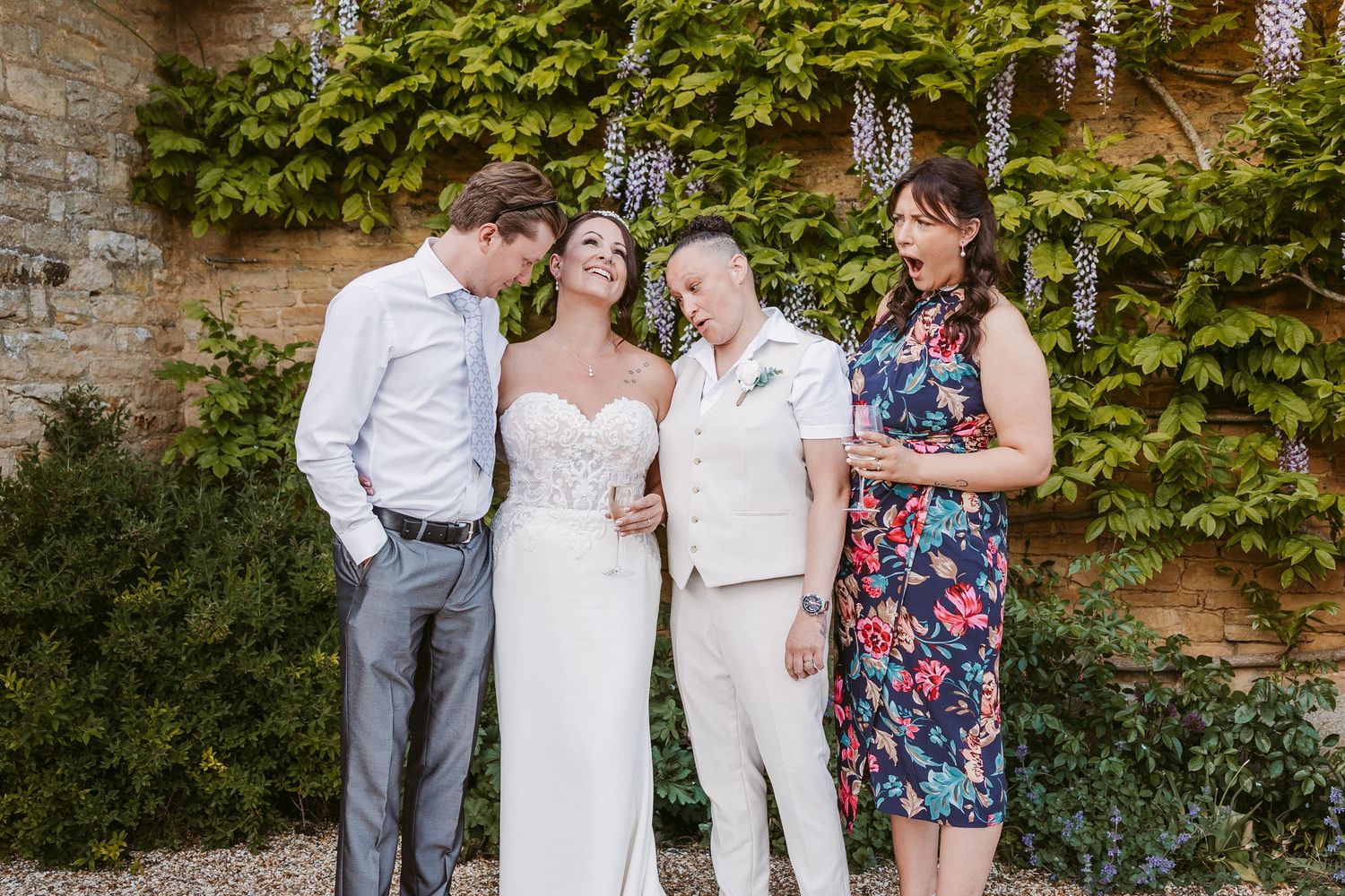 Wedding party gathered for photos against a vine-covered stone wall.