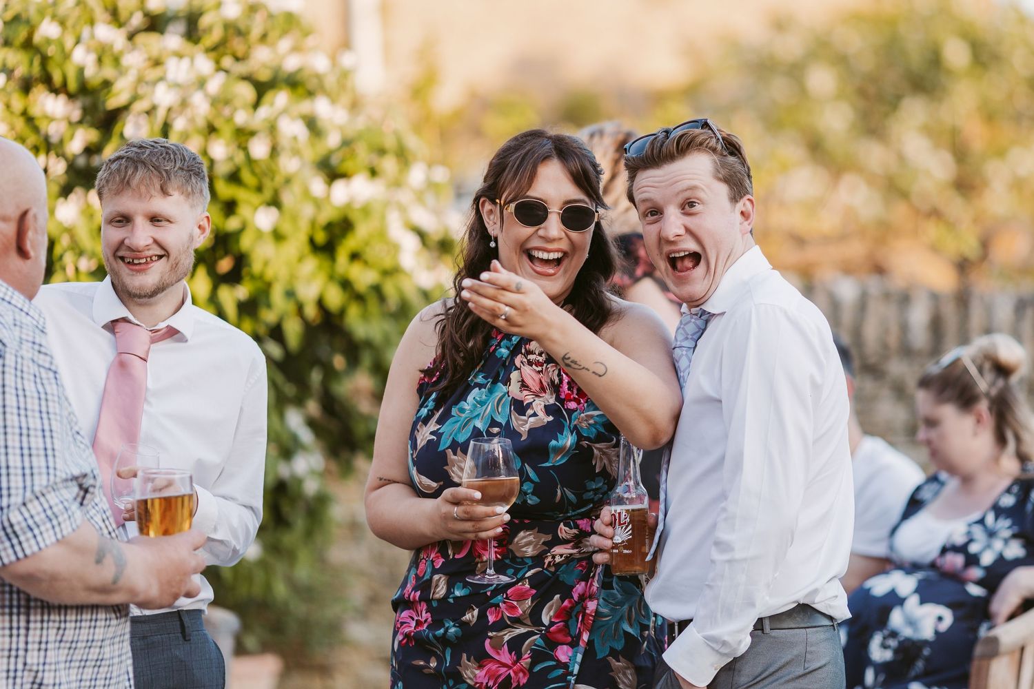 Wedding guests enjoying outdoor cocktail reception in garden setting during golden hour.