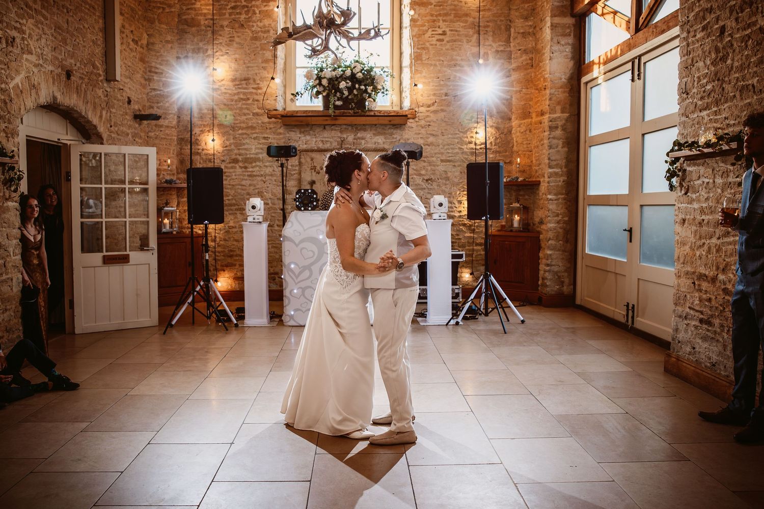 A couple shares their first dance in a rustic stone-walled venue with warm lighting and elegant decor.