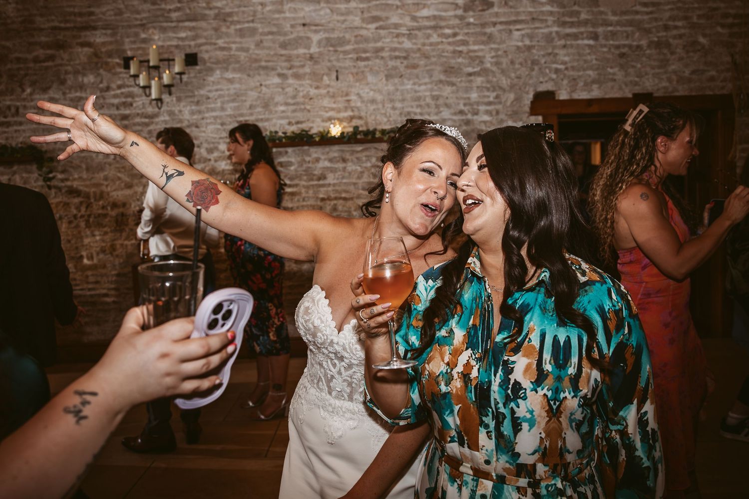 Wedding guests dancing and celebrating on a rustic brick-walled dance floor at a reception party.